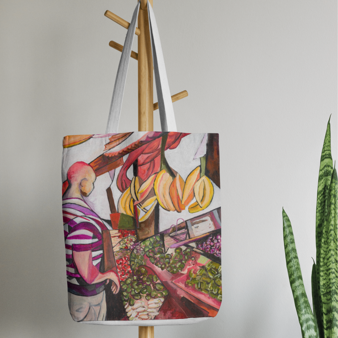 Tote bag with a colorful design of a person at a market hanging on a wooden coat rack.
