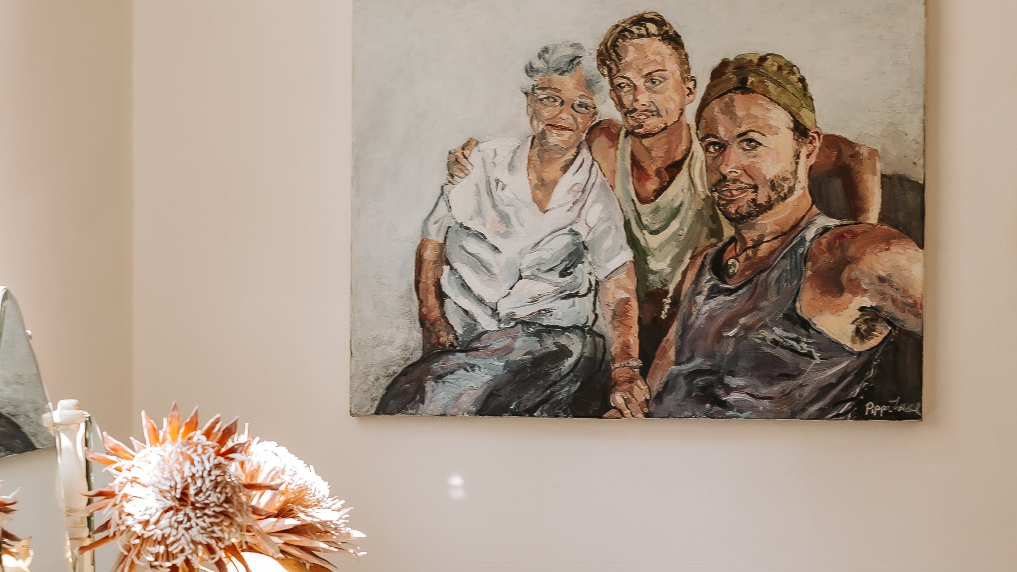 Portrait of three people hanging on a wall above a table with decorative items.