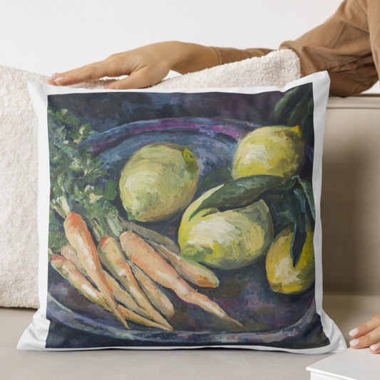 Decorative pillow with a painting of lemons and carrots on a white couch.