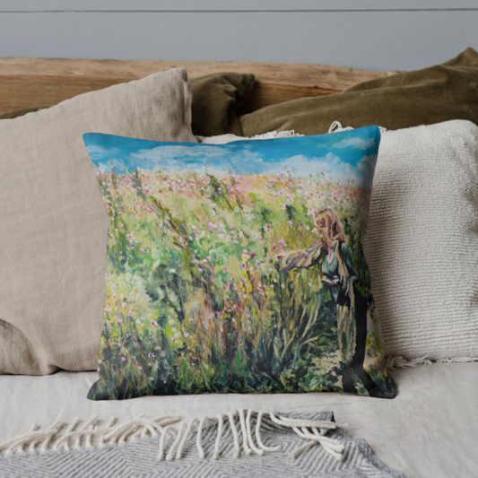 Decorative pillow with a colorful design of a person in a field on a sofa.